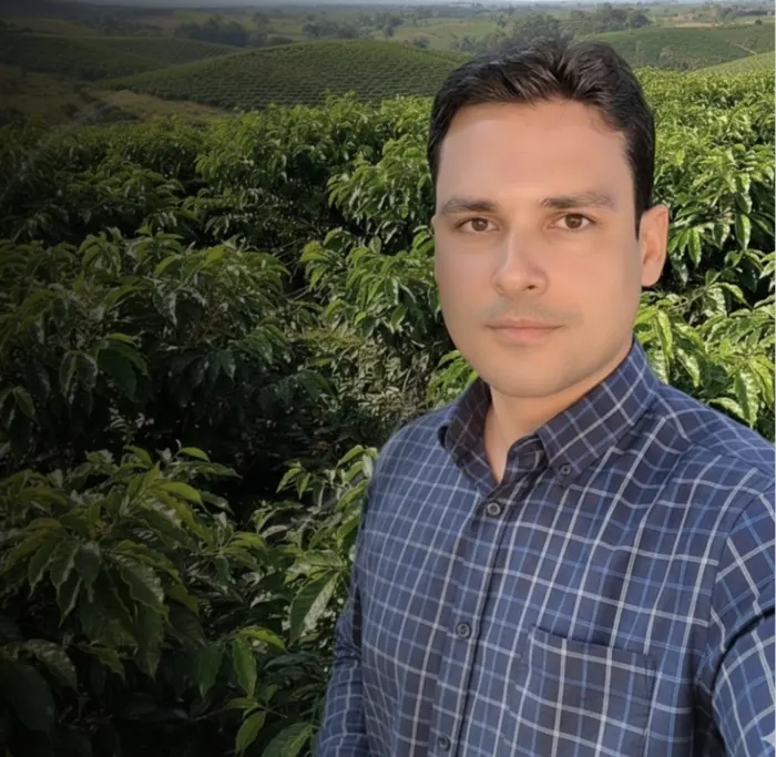 Stéfano Ferreira, advogado e produtor rural, em pé no meio de uma lavoura de café